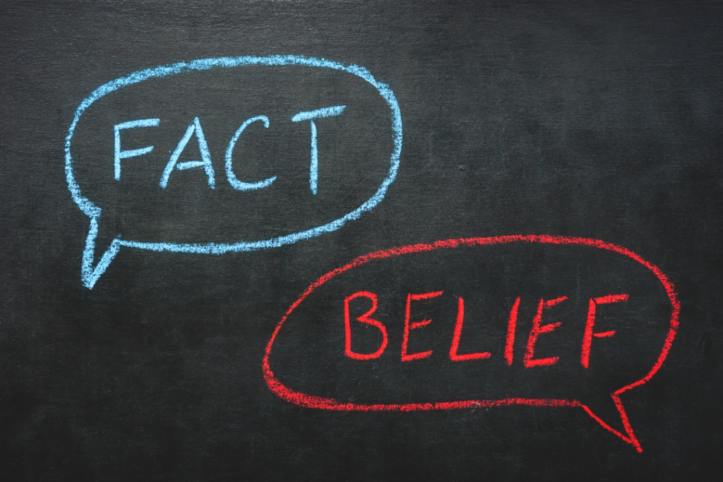 Obrazek przedstawiający dwie chmurki namalowane kredą na tablicy, jedna z napisem "Fakt", druga "Przekonanie" odnosi się do pracy nad zniekształceniami poznawczymi w terapii CBT